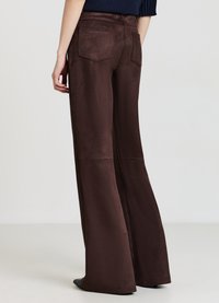 Braune Hosen mit weitem Bein aus glattem, mattem Stoff, mit Gesäßtaschen und tailliertem Bund. Der Saum reicht bis über die Oberseite der Schuhe.