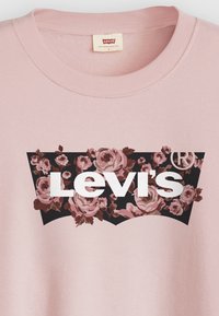 Sweatshirt rose à col rond, ornée d'un design floral noir et du logo "Levi's" en lettres blanches en gras à l'avant.