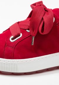 Baskets en daim rouge avec lacets en tissu, œillets argentés et semelle en caoutchouc blanche. Dotées d'une semelle extérieure texturée et d'un design à bout rond.