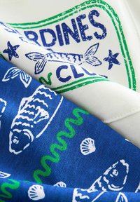Twee stofstukken: één crèmekleurig met een groen en blauw vissend print, en één blauw met witte vissen en schelpen, vantextuur katoen.