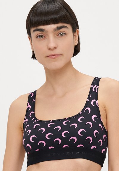 Top desportivo preto com padrão de lua crescente cor-de-rosa, decote quadrado e faixa elástica preta larga com logótipo da marca em relevo. Textura macia do tecido.