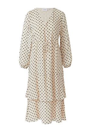 Polka dot dress featuring a V-neck, long sleeves, and a tiered design. Made of lightweight, textured fabric in cream with black dots.