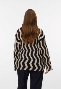 Pleteni pulover z geometričnim zigzag vzorcem v rjavi in kremni barvi. Ohlapen kroj z širokimi rokavi in teksturiranim zaključkom.