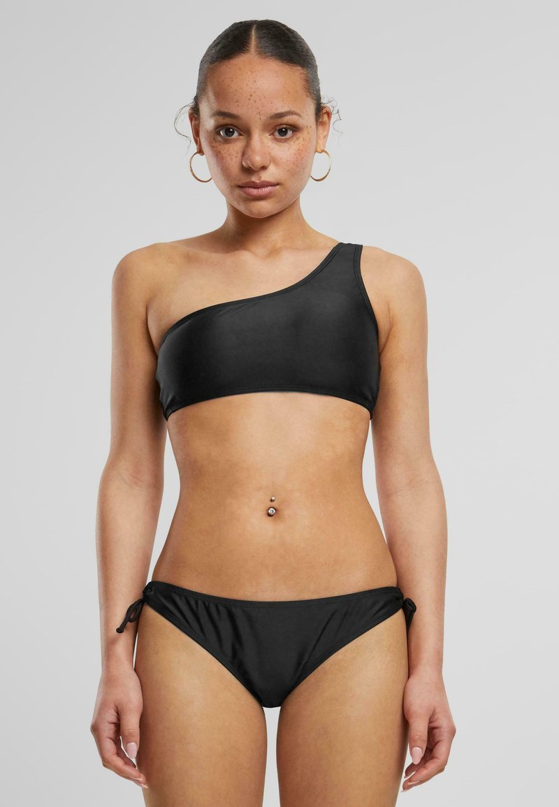 Black bikini set featuring a one-shoulder top and adjustable tie-side bottom, made from smooth, stretchy material.