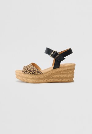 Wedge sandal featuring a black leather strap and a leopard print upper, with a textured cork-like platform for added height.