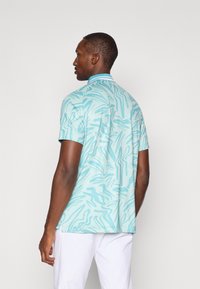 Camisa de mangas curtas em azul claro com padrões abstratos verdes, apresentando um colarinho e um corte descontraído, feita de tecido respirável.