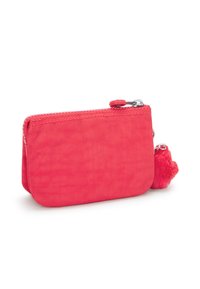 Petit étui zippé rose fabriqué en tissu lisse avec un pompon en fourrure attaché. Forme arrondie avec des bords cousus et une fermeture éclair contrastante.