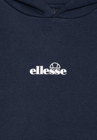 Mørkeblå bomullshoodie med hvit "ellesse"-logo og en rund design på forsiden. Myk tekstur med en klassisk hette-stil.