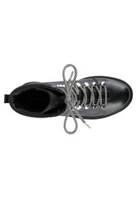 Botín de cuero negro con ojales plateados circulares, con cordones de patrones en blanco y negro y una lengüeta en la parte trasera.