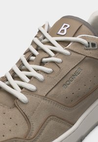 Baskets en daim beige avec lacets blancs, embossage "BOGNER" sur le côté, et logo "B" sur la languette, vues en gros plan.
