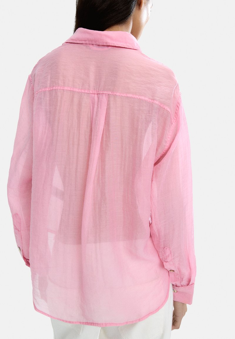 Lekka różowa koszula z przezroczystej tkaniny, z długimi rękawami i kołnierzem. Posiada mankiety na guziki oraz luźny krój z detalem w postaci plisek z tyłu.