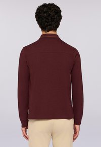 Camicia bordeaux a maniche lunghe con colletto, caratterizzata da una texture liscia, rifiniture a contrasto sul colletto e un design semplice e aderente.
