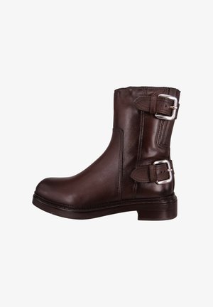 Brązowy skórzany botek za kostkę o gładkiej fakturze, z bocznymi klamrami i niskim, blokowym obcasem. Zdobiony przeszyciami wzdłuż podeszwy dla detalu.