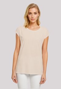 Light beige t-shirt made of soft fabric, features a round neckline and rolled sleeves, with a relaxed fit and straight bottom hem.
