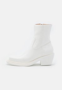 Botas de tobillo de charol blanco con punta redondeada y tacón cuadrado. Presentan un diseño elegante y paneles laterales elásticos para un fácil uso.