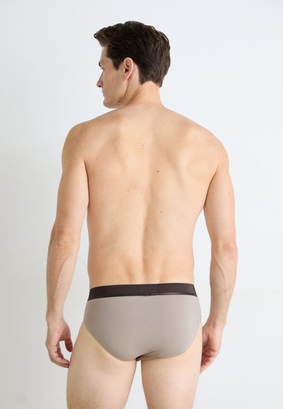 Grå boksershorts med mørkebrunt liv, laget av et glatt stoff, som viser en tettsittende design og minimal dekning.