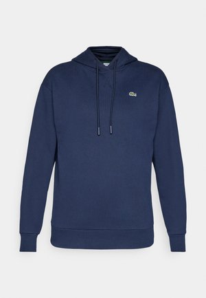 Námořnická modrá mikina s klokaní kapsou, kapucí na šňůrku a malým zeleným logem. Měkká tkanina z bavlněné směsi s žebrovanými manžetami a lemem.