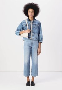 Denim jacket with front pockets, paired with light blue straight-leg jeans. Black flat shoes and a small cream crossbody bag.
