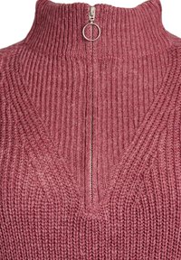Pull en tricot rose avec un col montant, présentant un zip à moitié et une texture côtelée, mettant en avant un design en V.