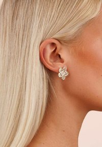 Guldtonade blommiga stiftörhängen med flera klara kristallaccenter, med en texturerad yta och en lökliknande design.