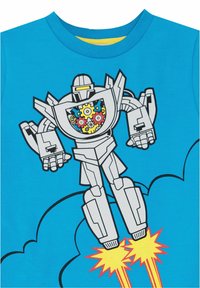 Camiseta azul con un gran diseño gráfico de un robot con un corazón mecánico, rodeado de engranajes coloridos y llamas de cohete.