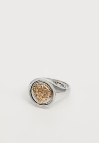 Anello in argento con un design centrale di testa di leone rotonda e texturizzata in oro. Superficie liscia con finitura lucida, con accenti minimali.