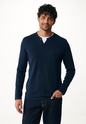 Camicia a maniche lunghe blu navy con scollo henley e dettagli con bottoni. Realizzata in tessuto liscio, abbinata a jeans denim scuri.