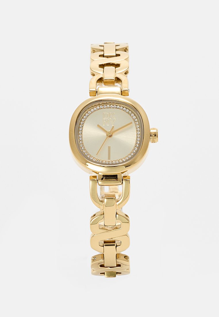 Reloj de pulsera dorado con una esfera redonda y texturizada, adornada con cristales. Presenta una pulsera de cadena entrelazada y un logo distintivo.