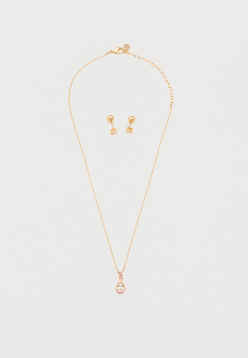 Χρυσό κολιέ με κρεμαστό μενταγιόν σε σχήμα δάκρυ με διαυγή πολύτιμη πέτρα και ταίριαστα χρυσά καρφωτά σκουλαρίκια με μικρές διαυγείς πέτρες σε λευκό φόντο.