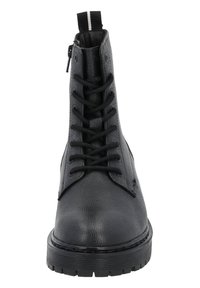 Bottines noires texturées avec un lacet, zips sur le côté, et une semelle noire épaisse avec un motif nervuré.
