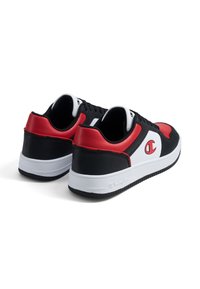Baskets noires et rouges avec une tige en cuir lisse, semelle en caoutchouc blanc et logo bien en évidence. Comprend un bout arrondi et un design à lacets.