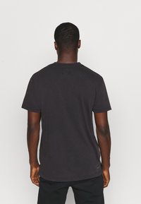 Czarny bawełniany t-shirt z okrągłym dekoltem, krótkimi rękawami i luźnym krojem. Charakteryzuje się gładką fakturą i minimalistycznym logo.