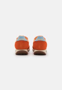 Orange suede sneakers with light blue accents, featuring a rounded heel, padded collar, and textured rubber outsole. "SAUCONY" logo on heel tabs.