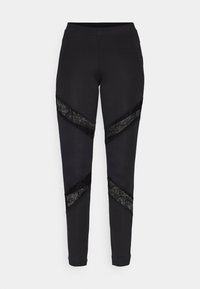 Mustat leggingsit, joissa on kolmion muotoisia leikkuja ja mustaa pitsiä sivuilla, valmistettu joustavasta kankaasta ja tiukasta muotoilusta.