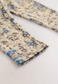 Leggings in tessuto con motivo floreale caratterizzati da una trama a coste. I colori includono verde tenue, blu e marrone con una finitura morbida.