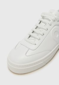 Sneaker in pelle bianca con finitura liscia, caratterizzata da una punta arrotondata, design con lacci e marchio sottile sulla linguetta. Suola in gomma piatta.