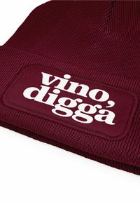 Maroon knit beanie with ribbed texture and a rectangular white patch displaying the text "vino, diggà." Sturdy, soft material for warmth.