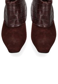 Stivali alla caviglia bordeaux con punta affusolata, caratterizzati da una finitura in suede liscio e un polsino in pelle con stampa coccodrillo.