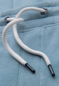 Lichtblauwe sweatshirt met witte koorden. De koorden hebben zwarte plastic uiteinden met het label "DUMARE." Zachte textuur met zichtbare stiksels.