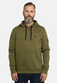 Olivgrüner Hoodie aus weichem Stoff, mit einer Fronttasche, Kapuze mit Kordelzug, schwarzen Akzenten und einem Logo auf der Brust.