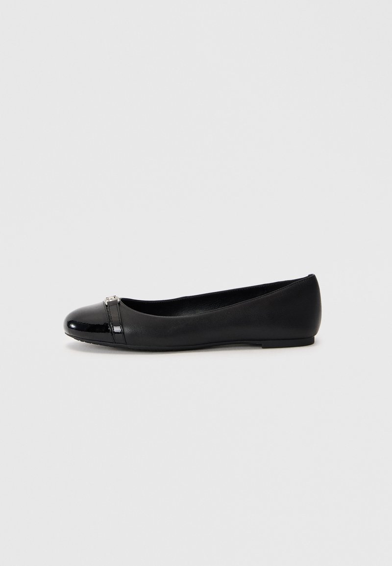 Shoe preto plano com bico redondo, apresentando uma tampa brilhante de patente e um corpo de couro texturizado, acentuado por um pequeno detalhe metálico.
