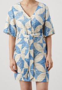 Robe à manches courtes en bleu et beige avec un motif de feuilles géométriques, dotée d'un col en V, d'une fermeture à boutons sur le devant et d'une ceinture à nouer à la taille.