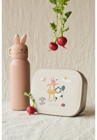 Svetloružová fľaša na vodu s dizajnom zajačika vedľa béžovej obedovej krabičky so zvieracími ilustráciami a reďkovkou s zelenými listami.