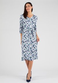 Bedrucktes Kleid mit V-Ausschnitt, drei Viertel-Ärmeln, einem bindbaren Taillengürtel und einem floralen Muster in Grüntönen, Blau und Weiß.
