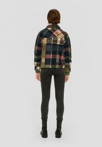 Chaqueta de forro polar con un patrón de cuadros multicolores en tonos verdes, negros y rosas. Cuenta con cuello tipo camisa y puños acanalados.