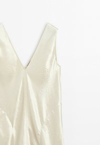 Cream-colored sleeveless dress with a deep V-neckline and subtle textured fabric visible on a white background.