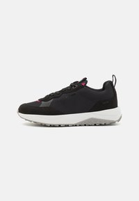 Black sneakers with a mesh upper and suede accents. Features a white midsole, gray textured outsole, and pink detailing near the laces.