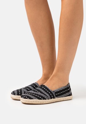 Espadrillas in bianco e nero con tomaia in tessuto intrecciato, pannelli elastici ai lati e suola in paglia, caratterizzate da un motivo a righe e una texture morbida.