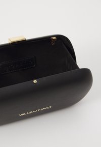 Pochette Valentino noire ouverte, montrant une fermeture en or, une texture lisse et une doublure en tissu intérieur avec l'étiquette de la marque à l'intérieur.
