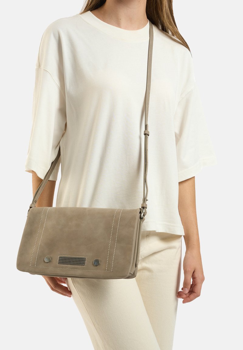 Grijze suède schoudertas met contrasterende stiksels, gestructureerde vorm, voorzijde met gaasdetail en een lange verstelbare schouderband, casual gedragen.